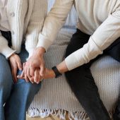 dos adultos de la mano en un sofa
