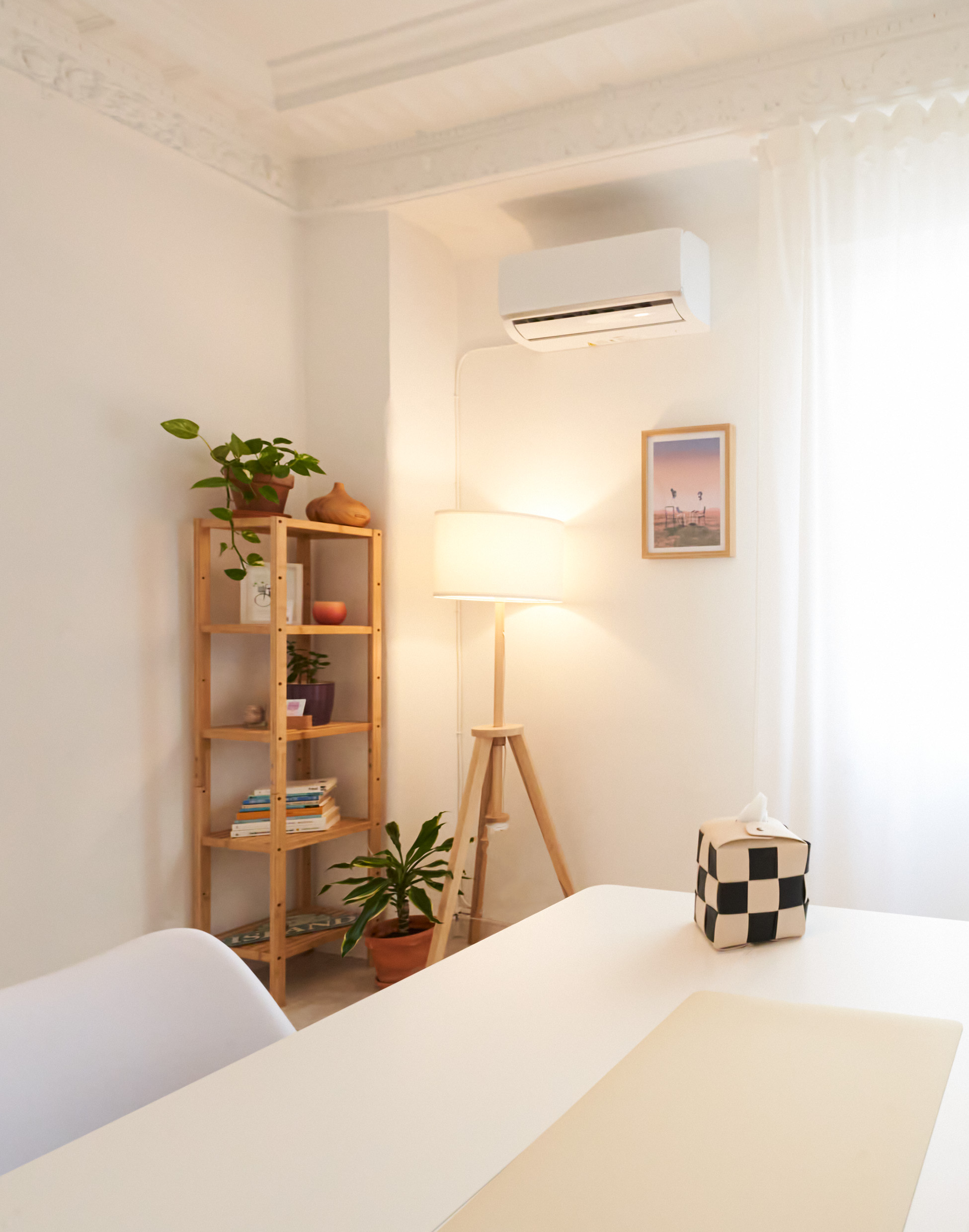 Despacho de psicara con mesa, estantería con plantas y lámpara de piel de madera y color cálida