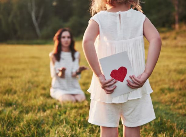 niña con carta de corazon para su madre en la naturaleza