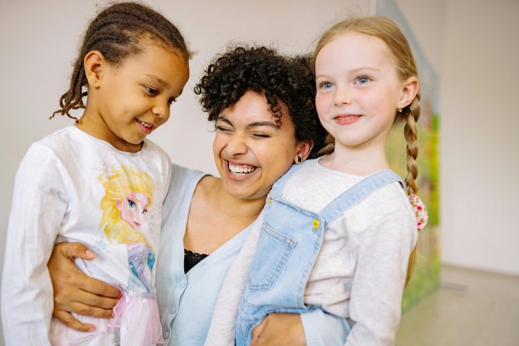 niños abrazados a profesora 