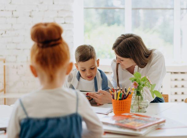 Niños en clase con una profesora hablando 